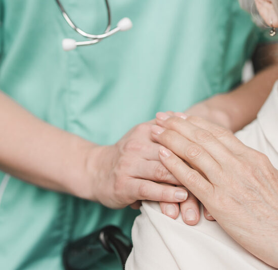 senior woman patient touching female nurse hand on shoulder